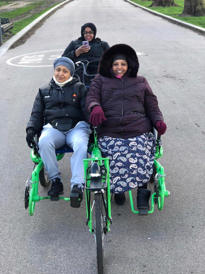 Picture of three women in the park on a recumbent bike for three people